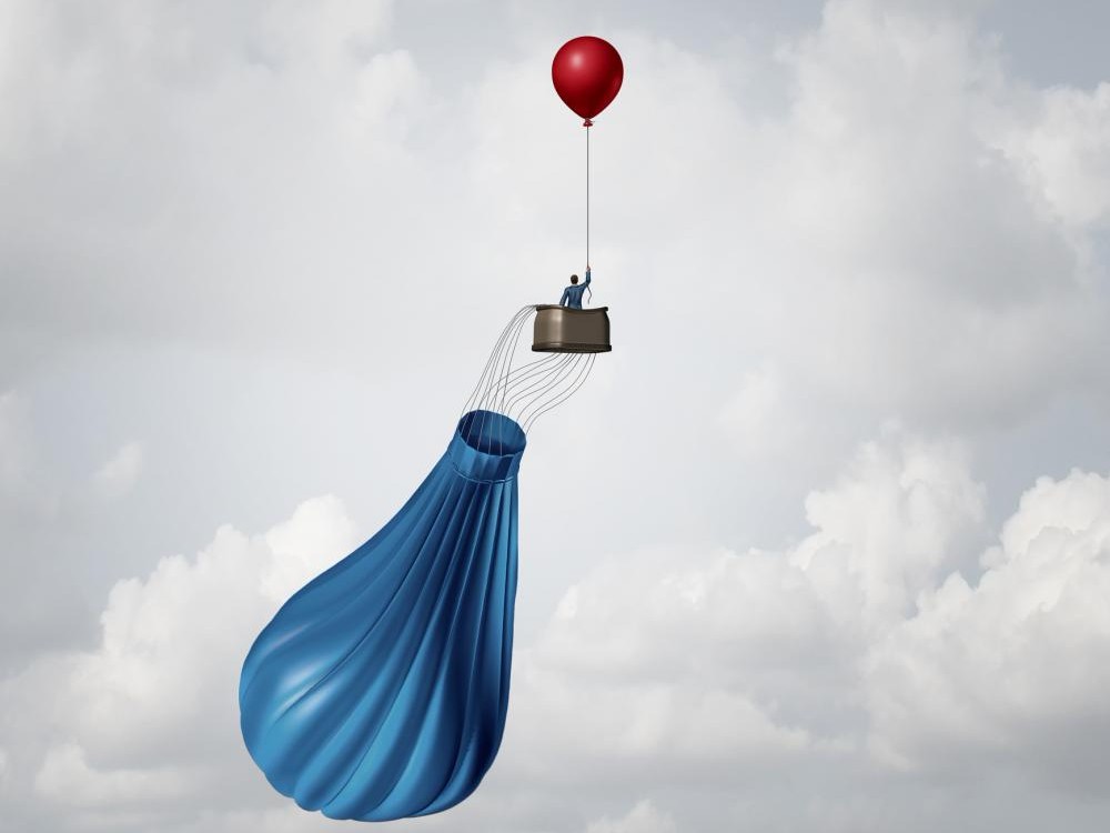 concept image: businessman uses emergency balloon in deflated hot air balloon basket