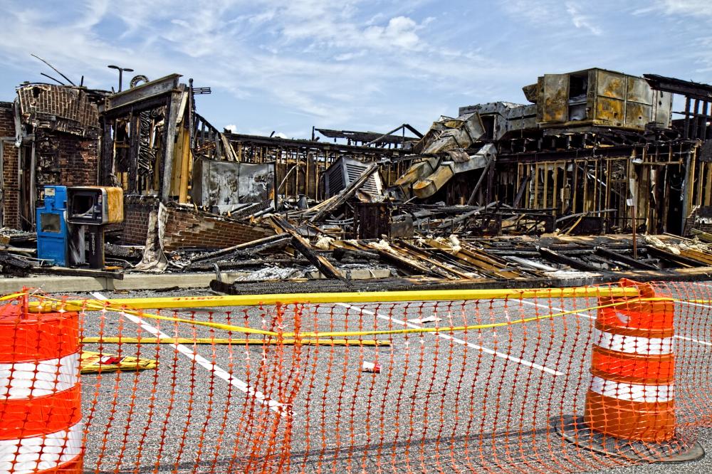 burnt down restaurant surrounded by orange safety cones and netting