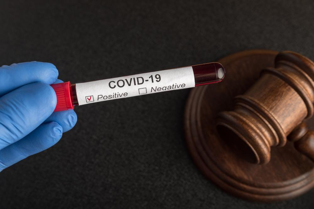 Blood samples in sample tube with label COVID 19 and judges gavel