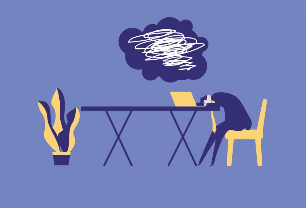 businessman slumped over desk with dark cloud full of scribbles hanging over him