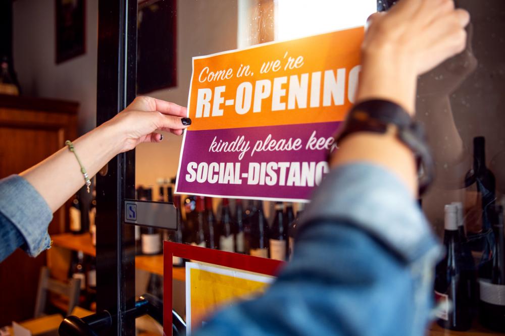employee placing reopening sign on door