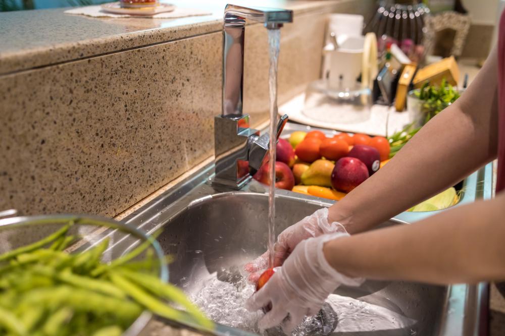 woman wearing gloves while washing fruits and vegetables