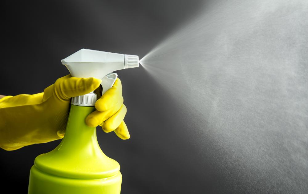 gloved hand spraying cleaner into air