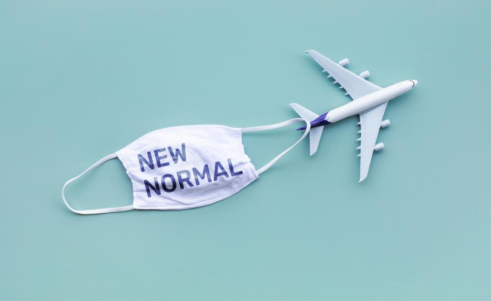Face mask that says "new normal" next to miniature airplane