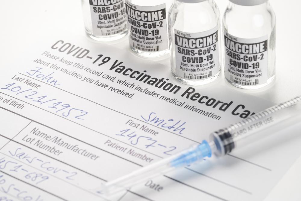 COVID-19 vaccination record card, syringe, and vials