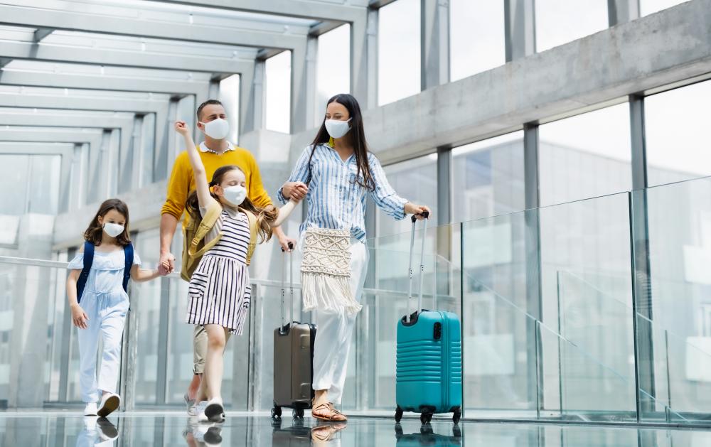 Family with two children going on holiday, wearing face masks through the airport