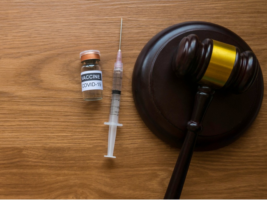 Top view of bottle of covid-19 vaccine, gavel and syringe on wooden background