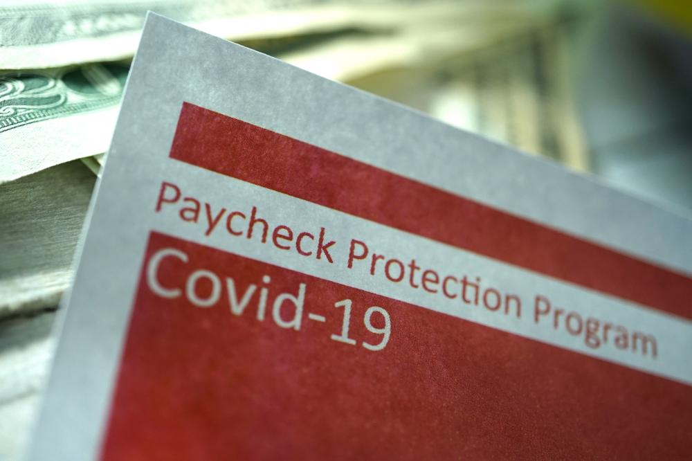 paycheck protection program for covid-19 paper next to stacks of bills