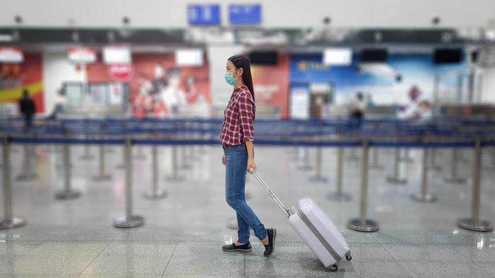 Asian tourist with luggage ,wearing mask to prevent during travel time at the airport
terminal