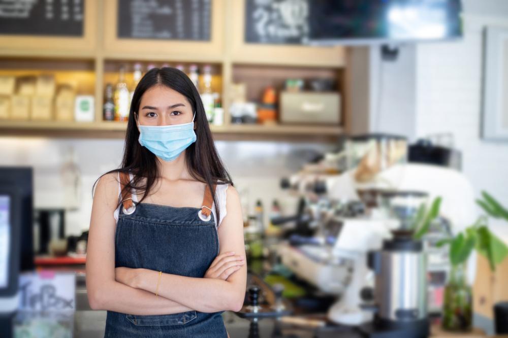 Asian business owner and barista wearing face mask