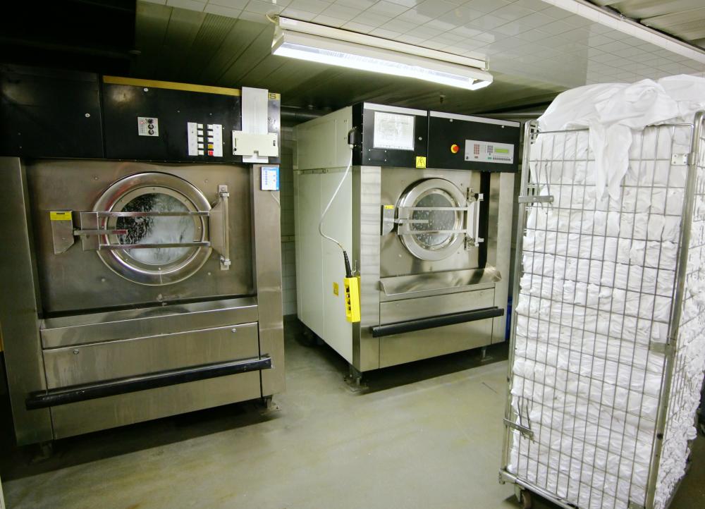 Industrial-sized washer and dryer with pile of white towels