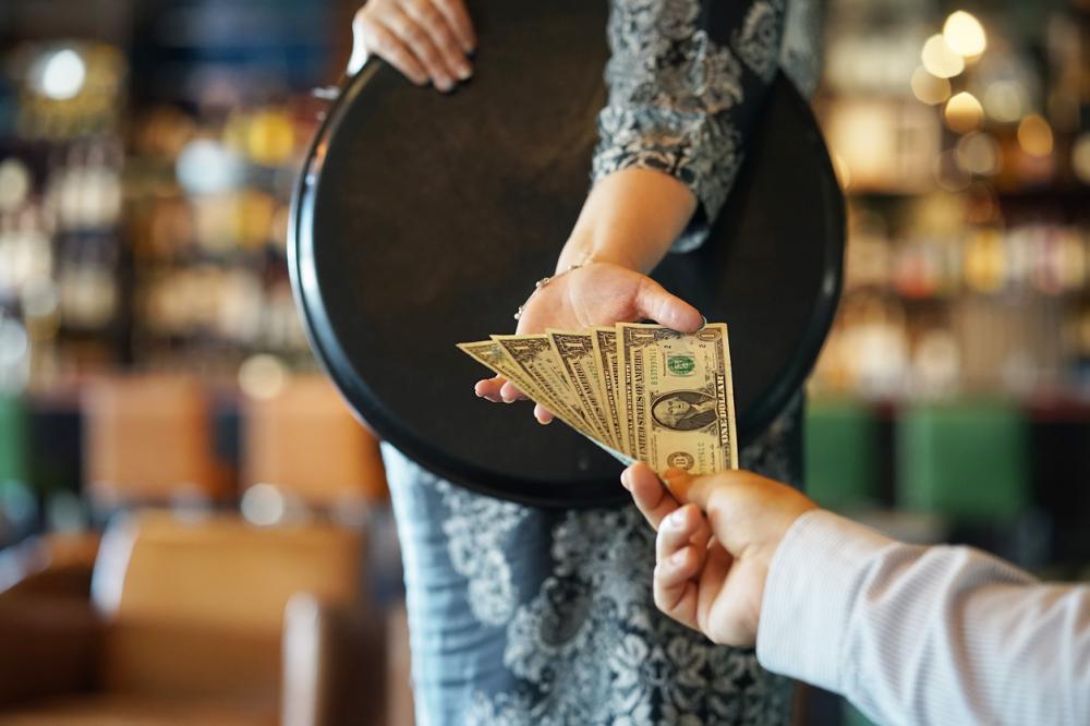 waitress taking dollar bills from customer