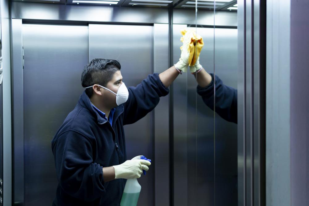 cleaning staff disinfecting elevator to avoid contagion