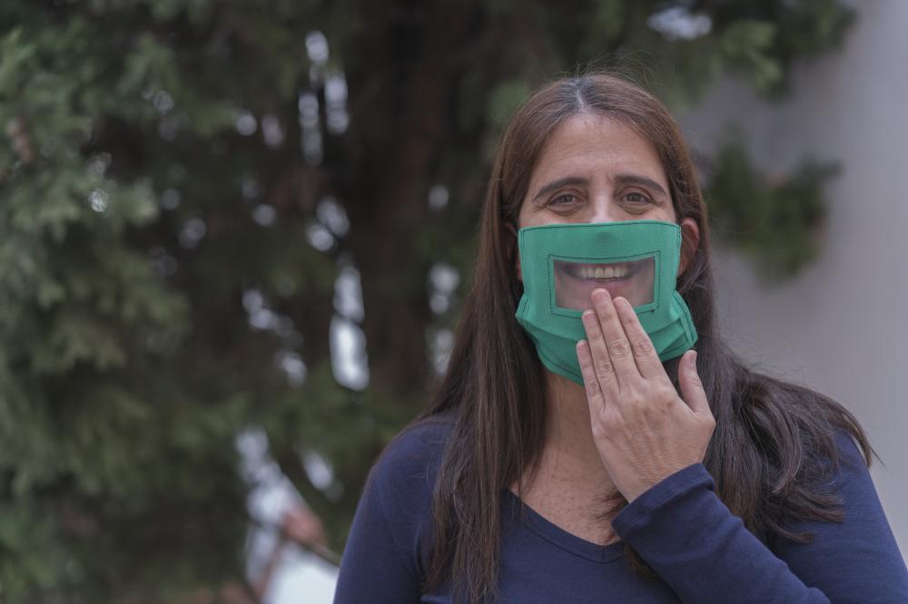 Happy sign language woman wearing transparent face mask and saying "Thank you" in ASL