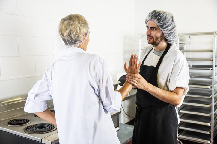 male food service worker improperly touching a female colleague in a commercial kitchen