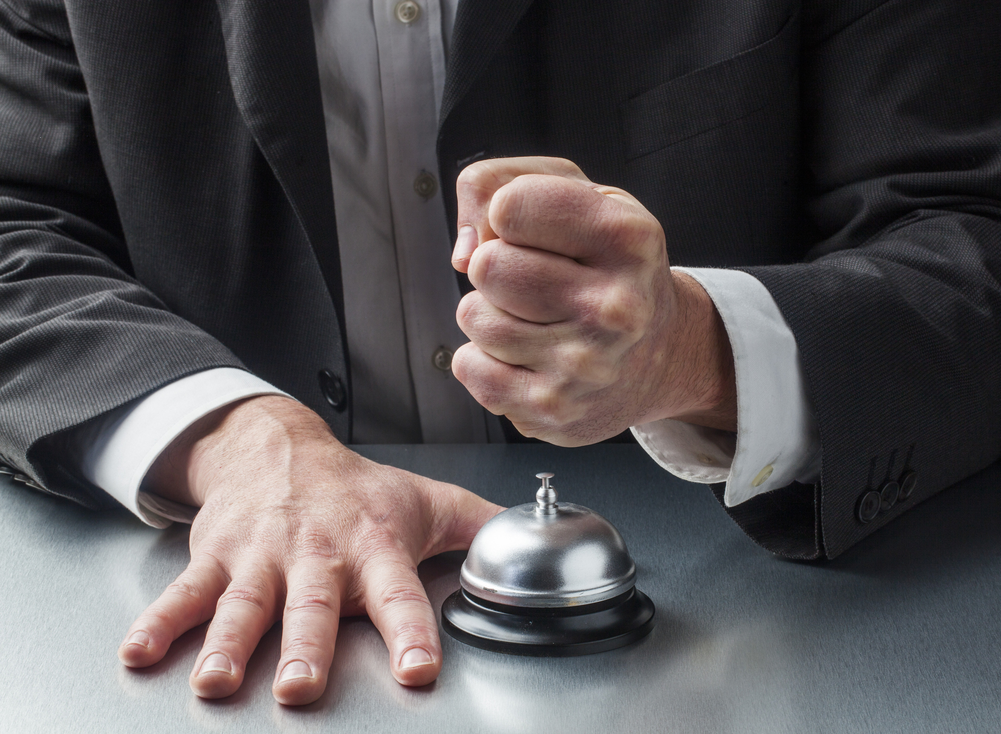 man in suit bringing down fist on service bell