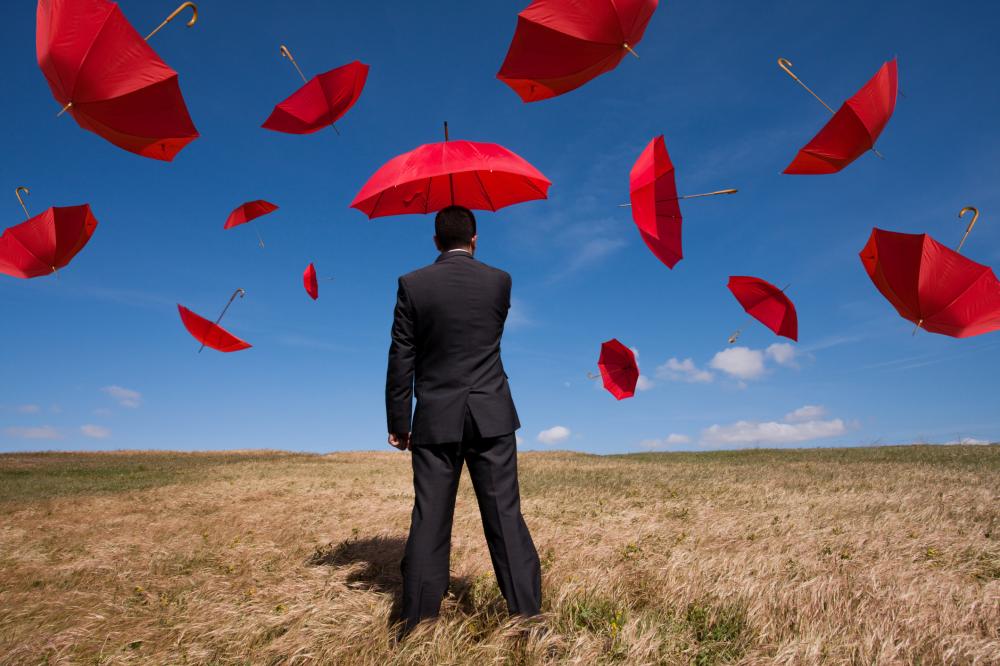 businessman surrounded by several flying red umbrellas